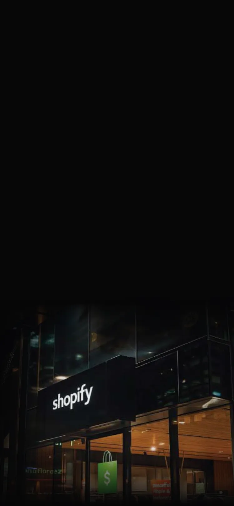 Shopify storefront lit up at night, fading into the dark section background