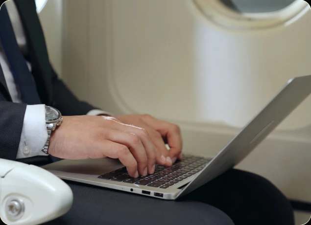 A businessman working on a laptop from an airplane seat