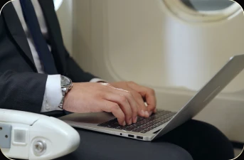 A businessman working on a laptop from an airplane seat